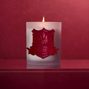 DMJ Home Fragrance luxury candle lit and surrounded by vibrant roses and wild florals on moss, styled for a high-end product shoot showcasing clean coconut wax craftsmanship and refined home fragrance design.