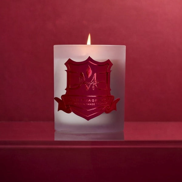 DMJ Home Fragrance luxury candle lit and surrounded by vibrant roses and wild florals on moss, styled for a high-end product shoot showcasing clean coconut wax craftsmanship and refined home fragrance design.