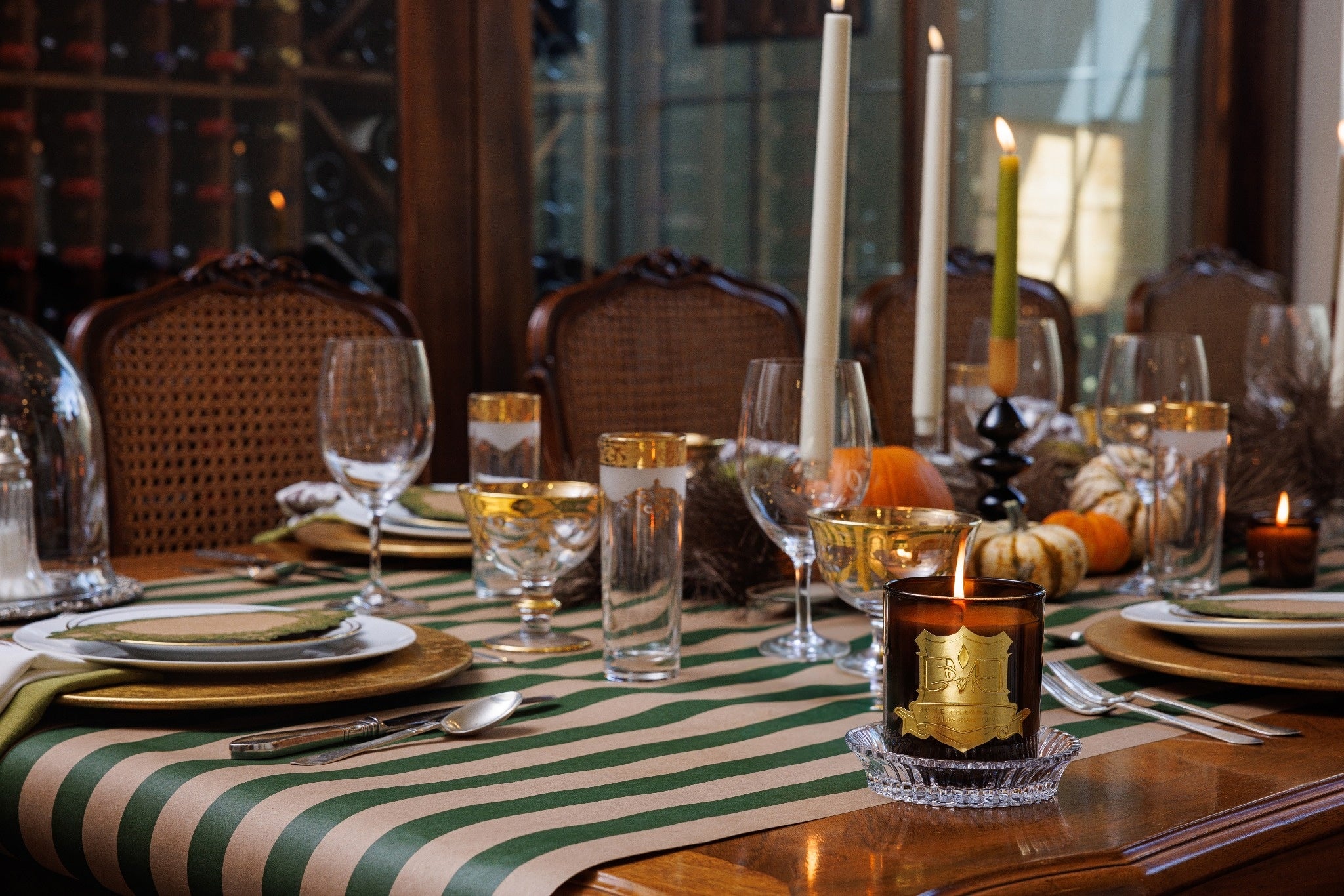 Dining table set for a meal with wine glasses, candles, and a bottle of wine.