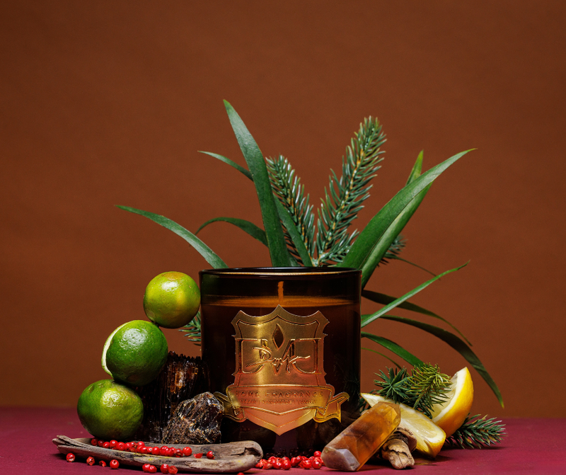 Candle with decorative elements including fruits and plants on a brown background