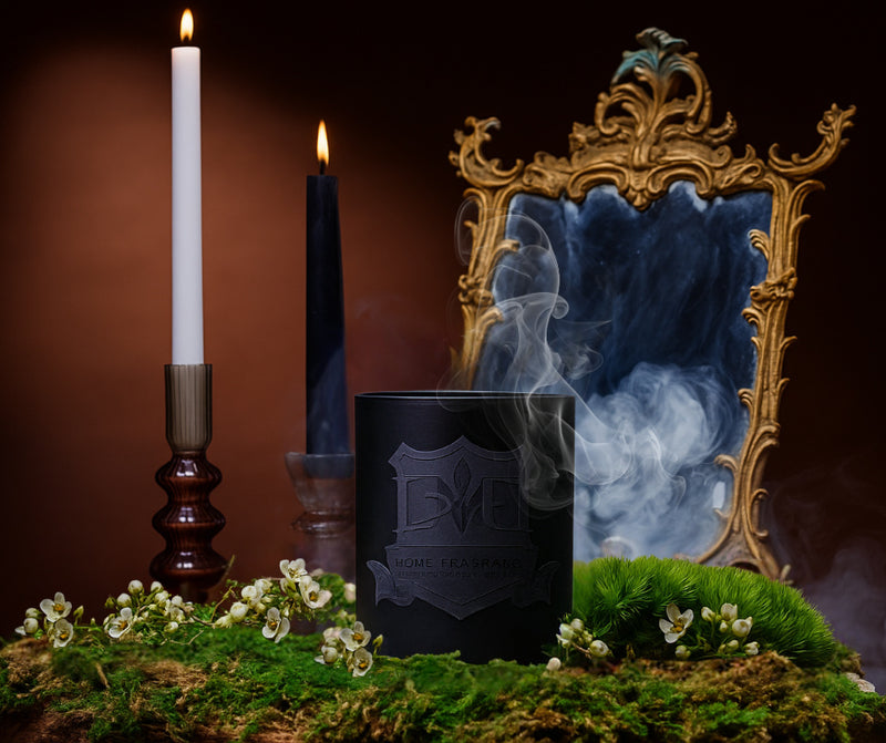 Decorative setup with candles, a bottle, and an ornate mirror on a dark background