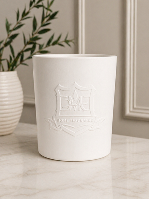 DMJ Home Fragrance Big Boy triple-wick candle styled on a marble countertop with olive branch accent, showcasing the embossed white ceramic vessel for luxury coastal home decor