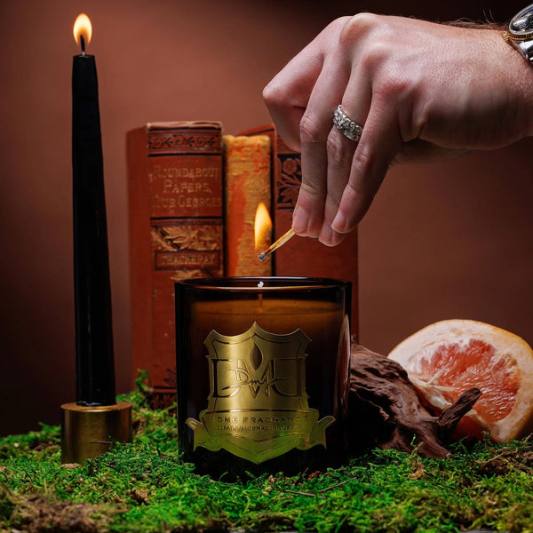 Lighting the Hemingway luxury candle by DMJ Home Fragrance with a match, styled with vintage leather books