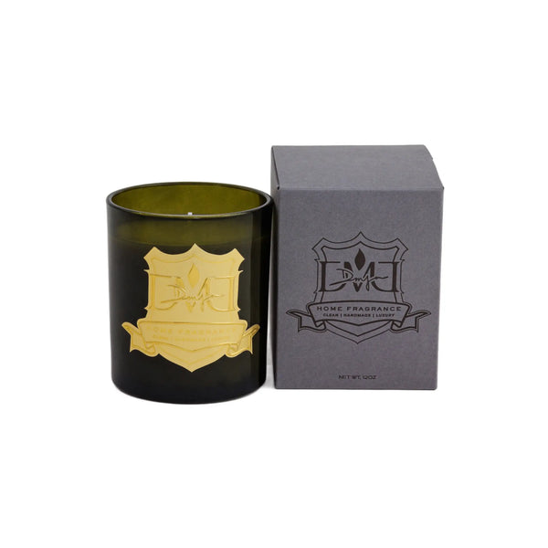 Woods candle by DMJ Home Fragrance in green glass with gold crest label beside its gray DMJ gift box